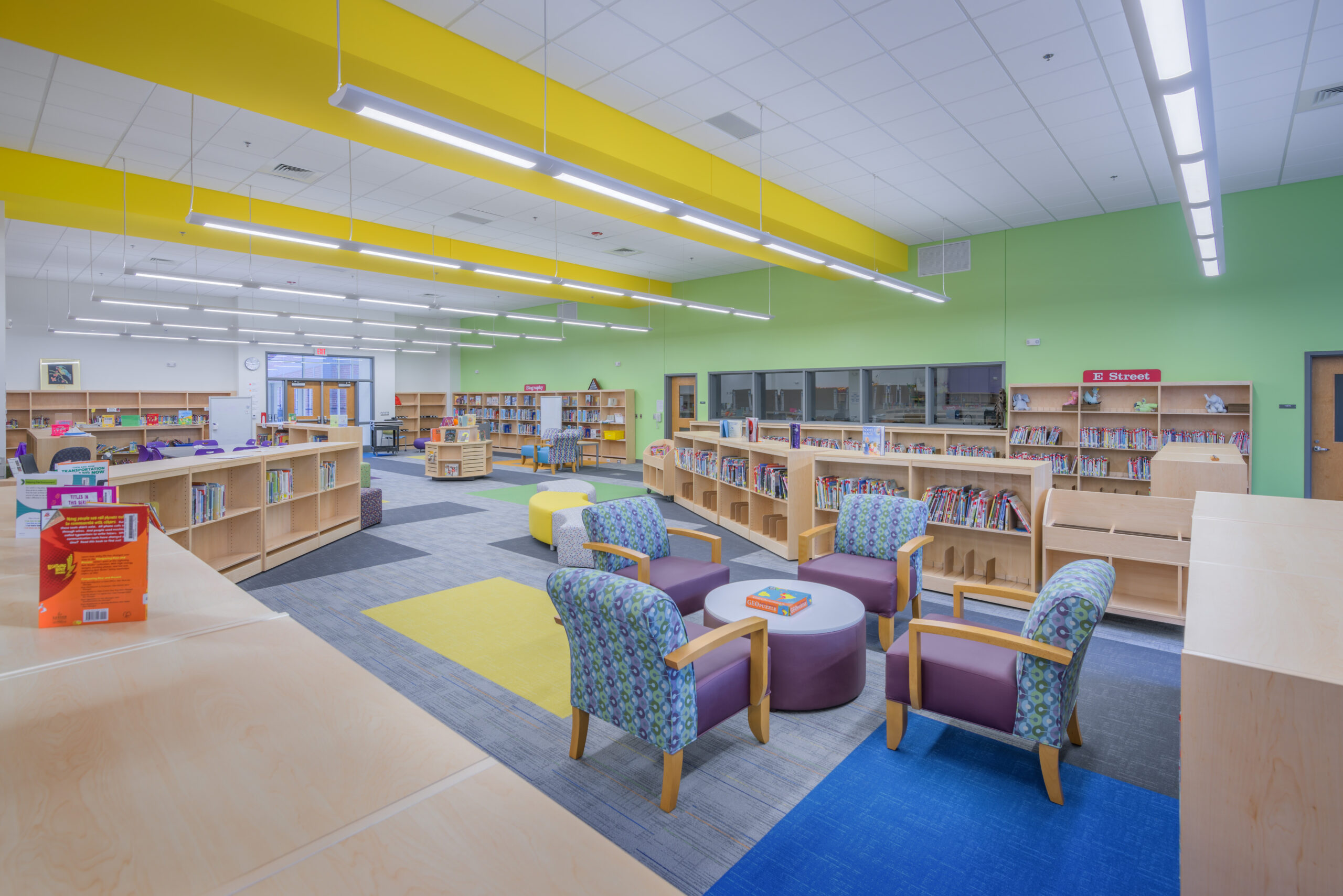 Barton Pond Elementary School Media Center Book Shelves with Books and Reading Spaces with Green Walls and a Color-Blocked Carpet
