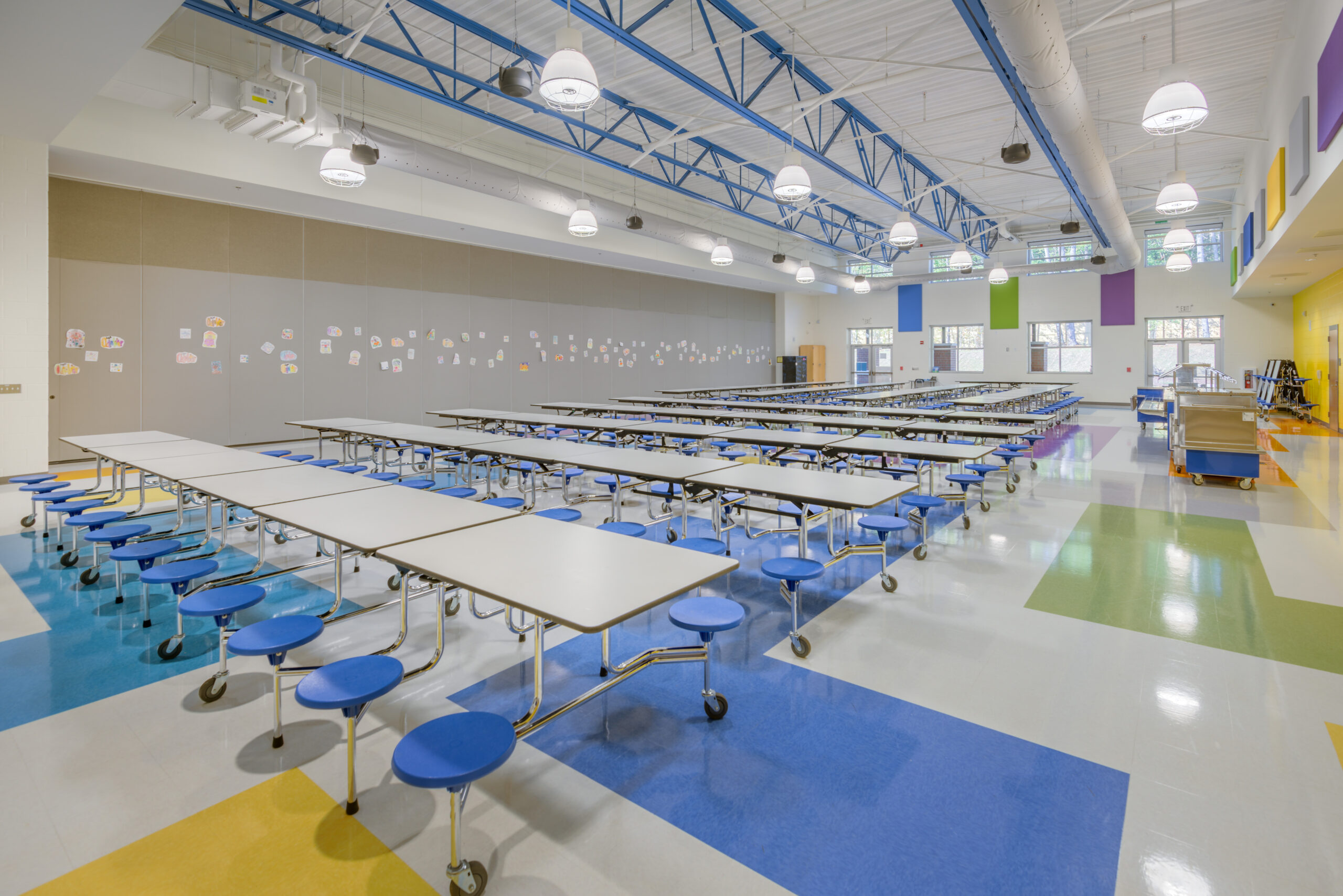 Barton Pond Elementary School Cafeteria with Foldable Lunch Tables with Attached Blue Stools for Students