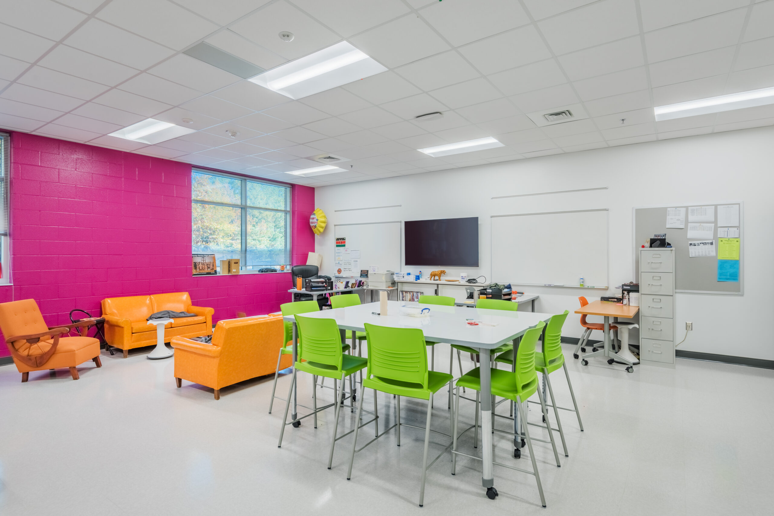 Fuquay-Varina High School Classroom with a Pink Accent Wall, Orange Couches, and Green Chairs