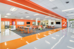 Fuquay-Varina High School Open Collaboration Area with Orange Walls, Orange Chairs and Tables, and Mounted TVs