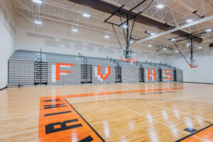 Fuquay-Varina High School Gymnasium Telescoping Bleachers with FVHS on the Front and Basketball Goals
